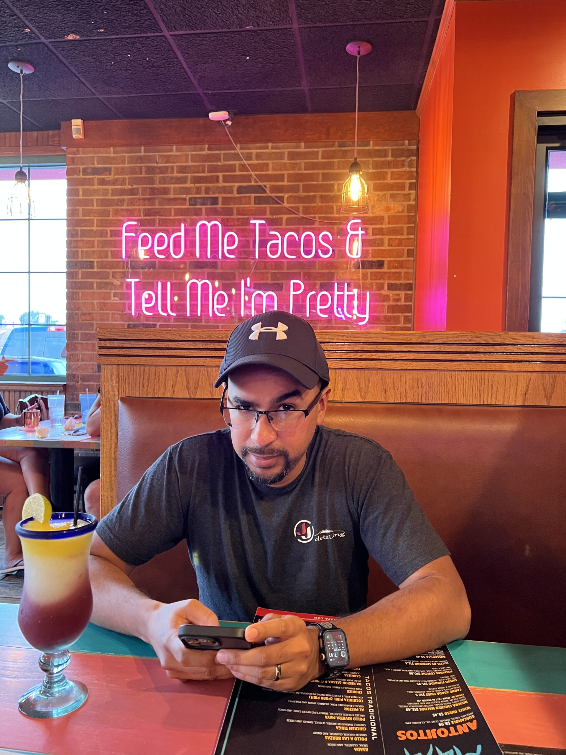 Lucio getting ready to order some tacos with a sign that reads "feed me tacos and tell me I'm pretty" behind him.